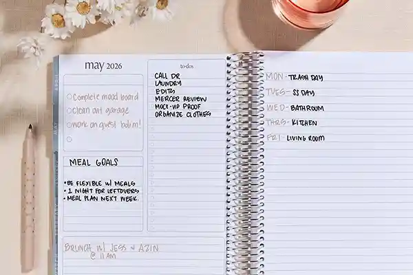 یک پلنر باز شده روی میز تحریر چوبی با خودکار و فنجان قهوه که حس نظم و شروع روز را منتقل میکند.